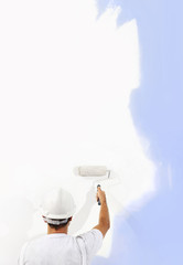 Rear view of painter man with paint roller painting on blank wall, isolated on white, copy space...