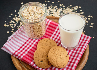 oatmeal cookies with glass of milk on tablecloth and wooden board