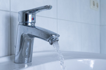 Close up of silver faucet in the bathroom with splashing water