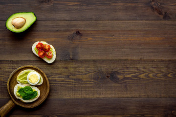 Healthy snacks. Set of toasts with vegetables like avocado, guacamole, rocket, cherry tomatoes on dark wooden background top view copy space