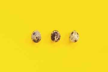 Three quail eggs on yellow paper background in minimal style. Easter concept. Template Creative Flat lay Top view Copy space lettering, text or your design