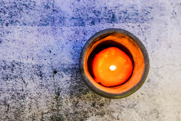Orange burning candle on marble background view from above