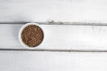 Flax seeds in white bowl on grey background, top view