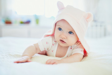 baby girl relaxing in bedroom in pink clothes or towel with ears