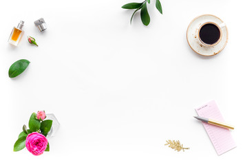 Home work desk, feminine workplace. Notebook and stationery near pink flowers and coffee on white background top view copy space frame