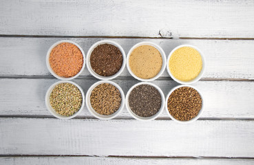 Collection of different groats on grey background. Top view of buckwheat, chia, flax, amaranth, lentils, couscous, wheat