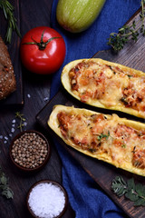 Stuffed zucchini halves roasted with cheese on a black cutting board