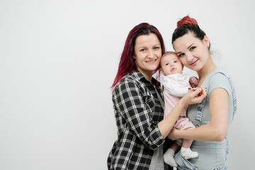 Two young women with a baby on a white background. Same-sex marriage and adoption, homosexual...