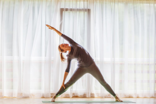 Caucasian woman is practicing yoga at studio