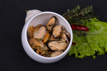 Pickled mussels in the bowl served pepper, garlic and salad