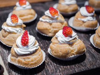 Fresh cream puffs filled with whipped cream and strawberry on top