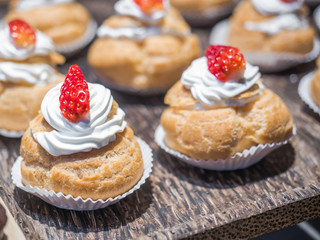 Fresh cream puffs filled with whipped cream and strawberry on top