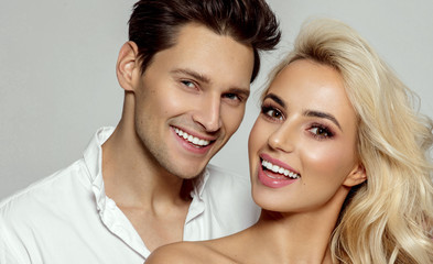 Portrait of attractive young smiling couple isolated over gray background