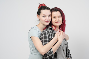 Two girls hug on a white background. Homosexual lesbian couple. Casual clothes.