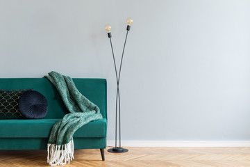 Minimalistic home interior with green velvet design sofa, black lamp and elegant blanket, pillow....