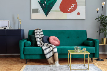 Luxury and stylish interior with green velvet design sofa, coffee table, lamp and commode. Grey...