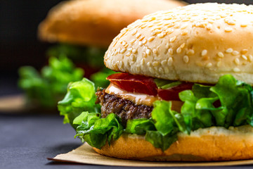Delicious fresh homemade burgers on a dark background. Fast and bad food