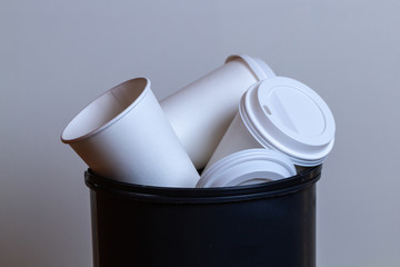 Garbage bin overflowing with paper, coffee cups. Coffee addiction and drinking a lot cups of coffee