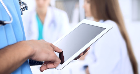 Surgeon doctor using tablet computer, close-up of hands at touch pad screen