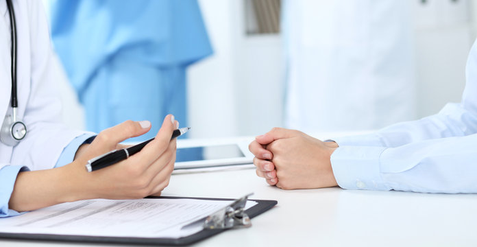 Doctor and patient discussing something, just hands at the table, white background