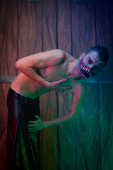 scary vampire male with huge teeth and bloody body as halloween body art standing in the night...