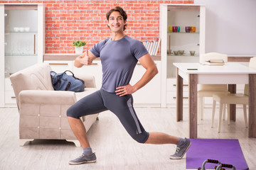 Young handsome man doing sport exercises at home 