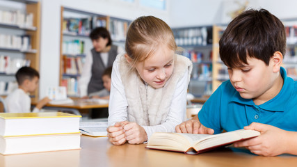 Fototapeta na wymiar Two school children reading in school library