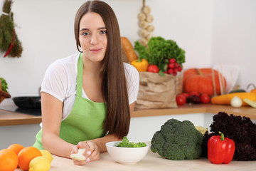 Young woman cooking in kitchen. Householding, tasty food and digital technology in lifestyle concepts