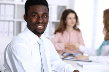 Fototapeta premium African american businessman at meeting in office, colored in white. Multi ethnic business people group
