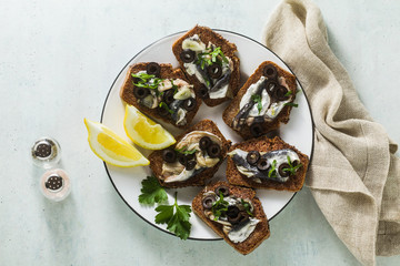 sandwiches with sardines marinated in olive oil with garlic and rye bread. summer light italian appetizer with lemon and parsleylive oil with garlic and rye bread. summer light italian appetizer