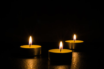 Three burning candles isolated on black background.