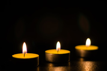 Three burning candles isolated on black background.