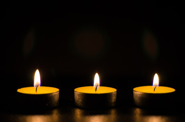 Three burning candles isolated on black background.