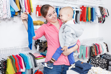 Female and her child are shopping and choosing child clothes