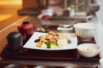 Grilled chicken and vegetables in a plate placed on the tray