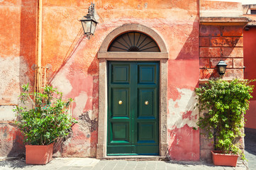 Fototapeta na wymiar Green door on the old red wall of the house. Rome, Italy.