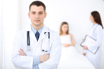 Fototapeta premium Medicine doctor standing and smiling on the background with patient in the bed