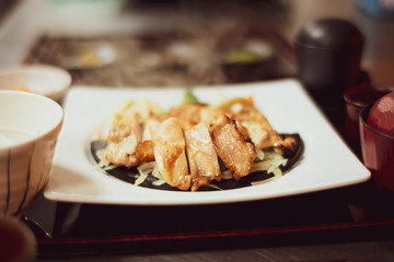 Grilled chicken placed on a hot stone in a white dish