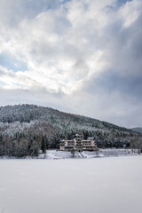 Fototapeta na wymiar Solitary building in beautiful snowy winter forest landscape, frozen Brezova dam, Shining movie style