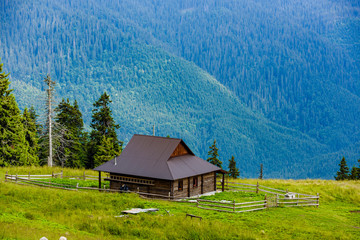 Beautiful mountains landscape with green meadow and modern wooden house