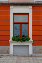Fototapeta na wymiar Colorful facade of modern building with window decorated with flowers