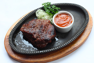 Steak with a cup of sauce, parsley and onion.