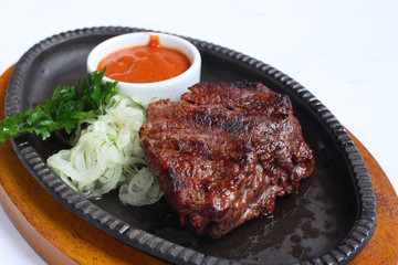 Steak with a cup of sauce, parsley and onion.