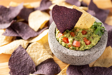 Granite Mulcajete filled with fresh guacamole surrounded by blue and yellow tortilla chips