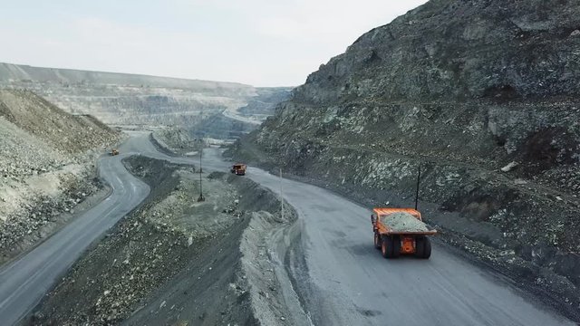 Top view of quarry dump truck. Dump truck traveling on dusty roads of open pit extraction of minerals. Heavy transport in extractive industry