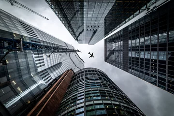 Foto auf Acrylglas Silhouette eines Düsenflugzeugs, das tief überfliegt Drei verschiedene Arten von Architektur mit kommerziellen Bürogebäuden außen in London © Stephen Davies