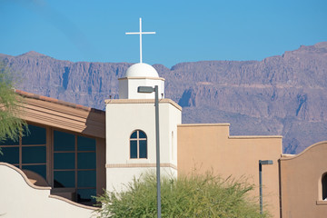 Part of a church building with a cross and mountains in the background
