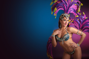 Attractive female cabaret dancer in costume with blue and purple feathers.