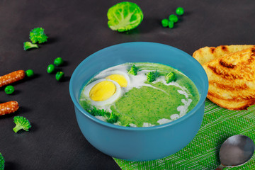 Homemade green peas and broccoli soup, dark wooden background,