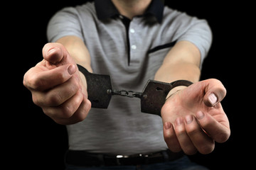 hands of the criminal are handcuffed against a black background.